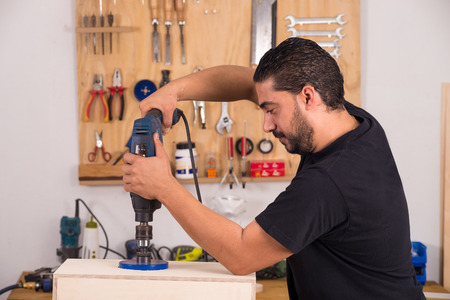 Artisan using a hole saw while crafting a cajon flamenco percussion instrumentの写真素材