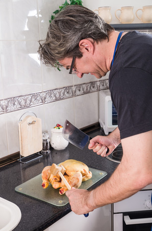 Clueless guy  trying to chop a chicken somehowの写真素材