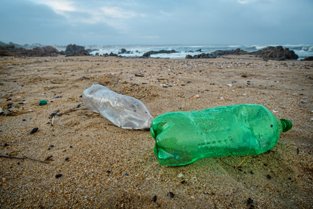 Plastic bottles and other rubbish polluting a sand beachの写真素材