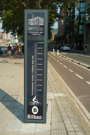 BILBAO, SPAIN - AUGUST  16, 2016: People walking next to a bicycle lane with a device that counts total bicycicle traffic, encouraging citizens to use it.のeditorial素材