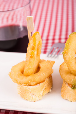 Spanish squid ring tapa served as pincho on bread with a glass of red wineの写真素材
