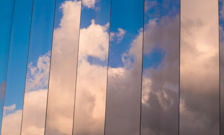 Clouds on blue sky reflected on the mirrored windows of a corporate buildingの写真素材