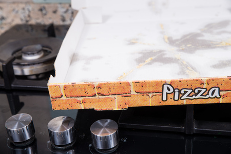 Used cardboard pizza box with grease stains lesft on its bottomの写真素材
