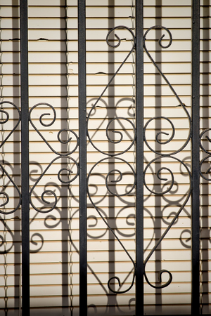 Cast iron bars on a window with lowered shuttersの写真素材