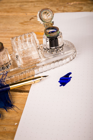 Dip pen in the shape of a quill on a document and next to an ink wellの写真素材