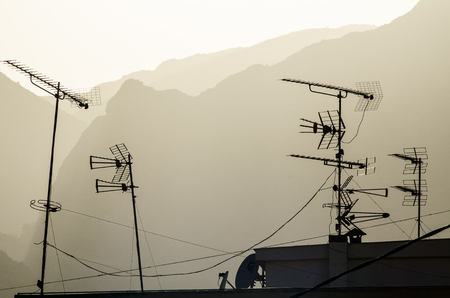 Several television antennae in quite a  chaotic distribution on top of a roofの写真素材