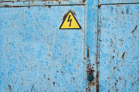Old door with shock hazard signの写真素材