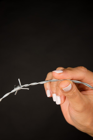 Female hand holding barbed wire, an immigration conceptの写真素材