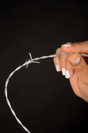 Female hand holding barbed wire, an immigration conceptの写真素材