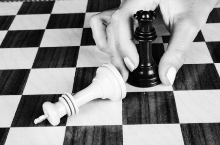 Female hand carrying a chess queen against the king, a concept