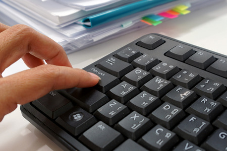 Office staff use the index finger to press the keyboard, cap lock, of a desktop computer at work....
