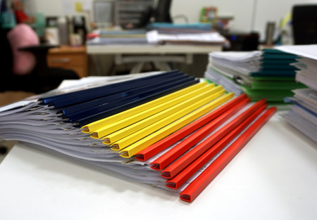 The colorful folders consists of  blue, yellow, red, posed a pile on the table to be used for...
