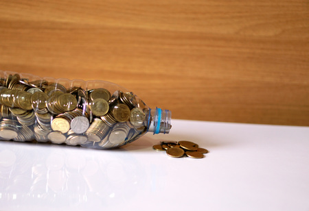 Coins and recycle plastic bottle on the desk.の写真素材