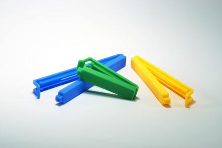 Blue, green and yellow plastic sealing clip isolated on white backgroundの写真素材