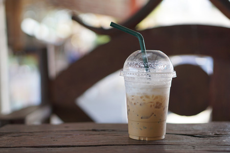 Ice coffee in plastic glass on wooden tableの写真素材