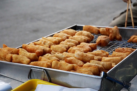Chinese dough  in the stainless steel tray for sell in morning market of Thailand.Blured street background.の写真素材