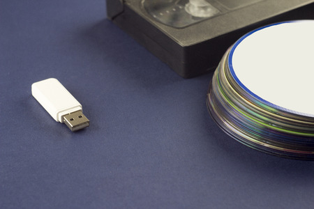 White flash drive on a blue background video cassette and compact discsの写真素材