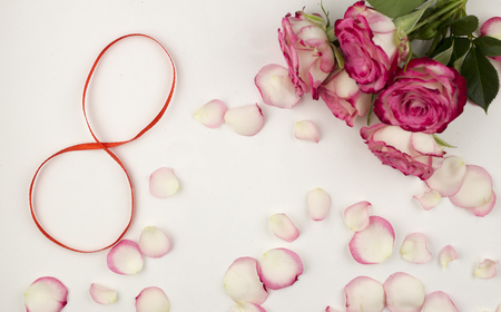 Digit 8 on white background and rose petalsの写真素材
