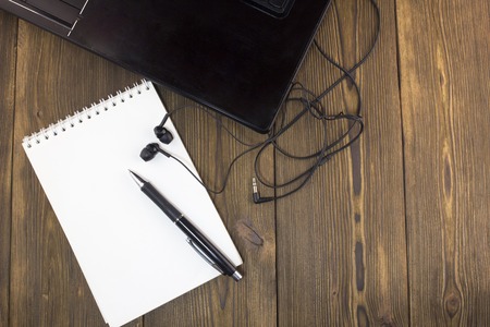Notebook headphones notepad pen on the table of woodの写真素材