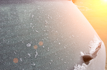 Frosted ice on car glass on sunset backgroundの写真素材