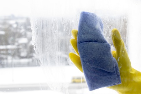 washing the window in yellow gloves, close-up