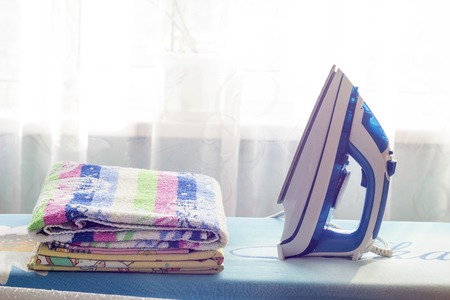 A pile of clothes and an iron on the ironing board
