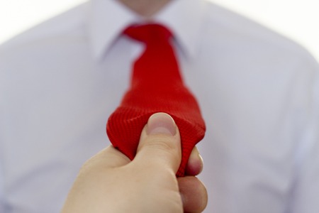 Girl holding a red tie a man in a white shirt, close-upの写真素材