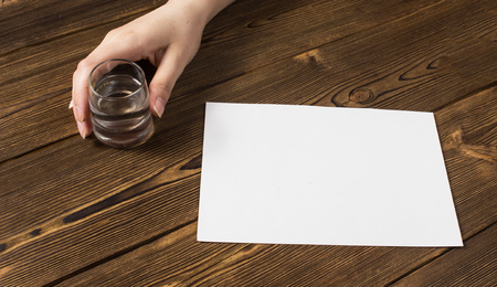 Female hand holding a glass of pure alcohol and ITPOs on the tableの写真素材