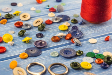 Threads and buttons on a blue wooden background