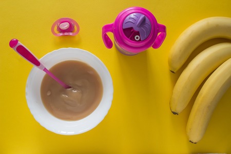 Baby porridge for baby and bananas on a yellow backgroundの写真素材