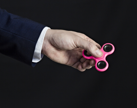 A man in a suit holds a spinner in his hand, a black background, a curtain planの写真素材