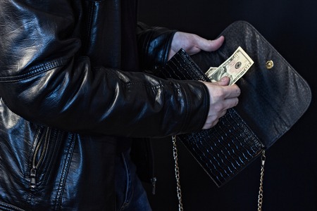A man steals money from a female bag, black background, close-upの写真素材