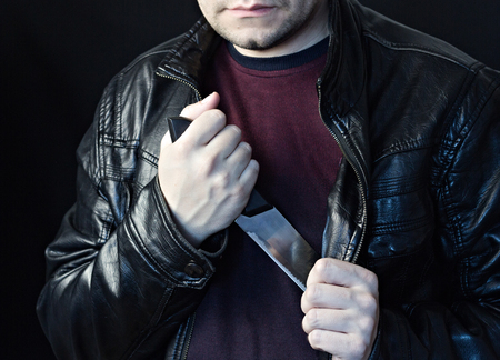 A man takes a knife out of a jacket, a black background