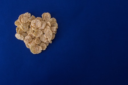 Corn flakes in the form of heart on a blue backgroundの写真素材