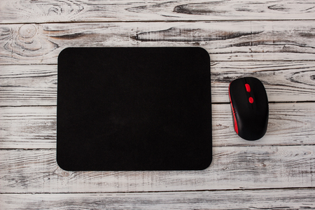 Black computer mousepad with a mouse on a white wooden backgroundの写真素材