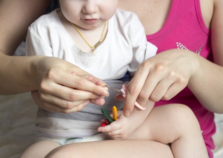 girl mother cuts her nails in the hands of a little girlの写真素材