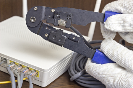 A man is squeezing a chip on a network cable, a modem, the Internet, a close-upの写真素材