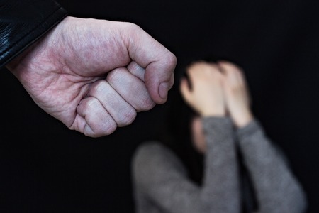 Male fist on black background, in the background a crying girlの写真素材