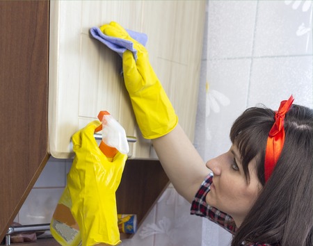 A girl in yellow gloves washes the locker in the kitchen, close-upの写真素材