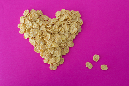Cornflakes on a pink background in the form of a heartの写真素材