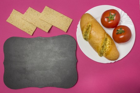 Breadstones on a pink background, a plate with a sandwich and tomatoes, a signboard, a breakfast for the child in school, pink backgroundの写真素材