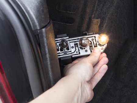 Male hand, replacement of a light bulb in the rear headlight of a car, close-up, taillightの写真素材