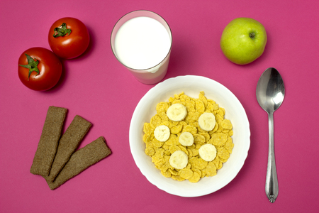 Breakfast child in school, corn flakes with milk, apple, bread on pink background, morningの写真素材