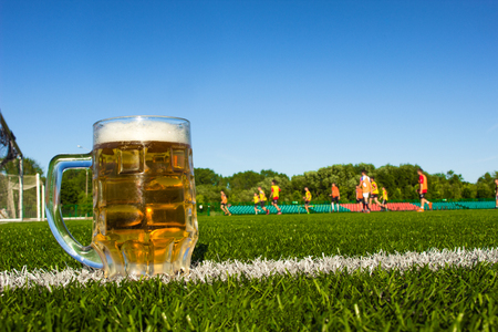 A glass of beer is on a football field, football is played in the stadium, stadium and a glass of beerの写真素材