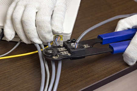 A man is squeezing a chip on a network cable, a modem, the Internet, a close-up, handsの写真素材