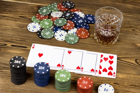 Poker chips, alcohol in a glass, cards on a wooden background, a game of poker, close-upの写真素材