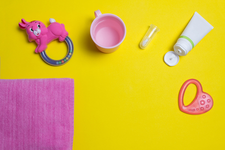 Brush for cleaning teeth and pasta, children's toy, towel and cup on a yellow background, toothpasteの写真素材