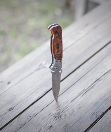 Folding knife stuck in a wooden table, close-up, knifeの写真素材