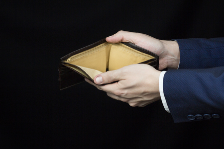 Male businessman holding a blank purse on his arms outstretched, close-up, black background, economicの写真素材