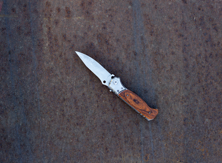 Folding knife on rusty metal background, close up, folding knifeの写真素材
